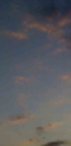 MATTHEW SWARTS A CLEAR SKY AT DUSK WITH SCATTERED, SOFT PINK CLOUDS AGAINST A GRADIENT OF BLUE AND GRAY TONES.