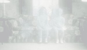 MATTHEW SWARTS TWO FAINT, TRANSLUCENT CHILDREN SIT ON A FLORAL-PATTERNED COUCH IN A DIM, SOFTLY-LIT ROOM WITH CURTAINS AND LAMPS, CREATING A GHOSTLY, ETHEREAL EFFECT—A HAUNTING CONTEMPORARY VISUAL REMINISCENT OF MATTHEW SWARTS.