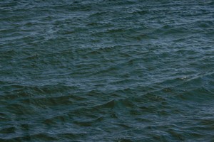 MATTHEW SWARTS DEEP BLUE-GREEN OCEAN WATER WITH SMALL, GENTLE WAVES AND RIPPLES, CREATING A TEXTURED SURFACE ACROSS THE IMAGE.