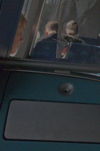 MATTHEW SWARTS A WOMAN SITS BY A WINDOW ON A TRAIN OR BUS IN NORWAY, LOOKING DOWN. REFLECTIONS OF TWO OTHER PEOPLE, ONE WEARING A CAP, ARE VISIBLE IN THE GLASS ABOVE HER. THE DIMLY LIT SCENE WITH BLUE SEATS EVOKES MATTHEW SWARTS’S CONTEMPLATIVE ART.