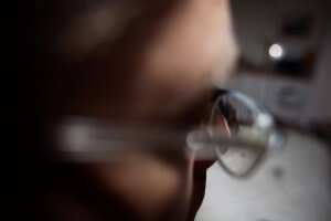 MATTHEW SWARTS A CLOSE-UP, BLURRED IMAGE OF A PERSON WEARING EYEGLASSES, WITH THEIR FACE PARTIALLY VISIBLE AND THE BACKGROUND OUT OF FOCUS, EVOKES A CONTEMPORARY VIBE REMINISCENT OF AN ANIMATION OR VIDEO STILL.