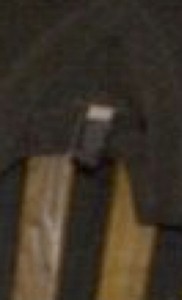 MATTHEW SWARTS A BLURRY CLOSE-UP IMAGE SHOWING A SMALL RECTANGULAR BLACK AND WHITE OBJECT AGAINST A DARK BACKGROUND WITH SOME LIGHTER BROWNISH VERTICAL LINES.