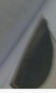 MATTHEW SWARTS A CLOSE-UP, BLURRY IMAGE SHOWING A CURVED, DARK OBJECT AGAINST A LIGHT BACKGROUND WITH A DIAGONAL LINE, MAKING IT DIFFICULT TO IDENTIFY SPECIFIC DETAILS.