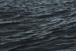 MATTHEW SWARTS DARK, RIPPLING OCEAN WATER WITH TEXTURED WAVES AND SUBTLE HIGHLIGHTS REFLECTING ON THE SURFACE, CREATING A MOODY AND DRAMATIC ATMOSPHERE.