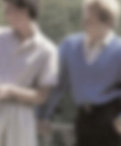 MATTHEW SWARTS TWO PEOPLE STANDING CLOSE TOGETHER OUTDOORS. THE IMAGE IS BLURRED, BUT ONE APPEARS TO WEAR A LIGHT SHIRT AND THE OTHER A LIGHT BLUE SWEATER OVER A COLLARED SHIRT. GREEN FOLIAGE IS VISIBLE IN THE BACKGROUND.