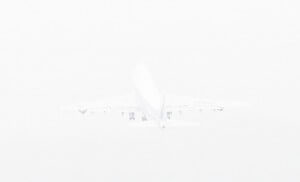 MATTHEW SWARTS A WHITE AIRPLANE IS TAKING OFF, SEEN FROM BEHIND, AGAINST A BRIGHT, HAZY SKY.