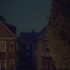 MATTHEW SWARTS A VISUAL, CONTEMPORARY SCENE AT NIGHT SHOWS TWO HOUSES WITH DARK WINDOWS, A NARROW DRIVEWAY BETWEEN THEM, A PARKED CAR, AND A LARGE TREE ON THE RIGHT, ALL UNDER A DARK BLUE SKY.