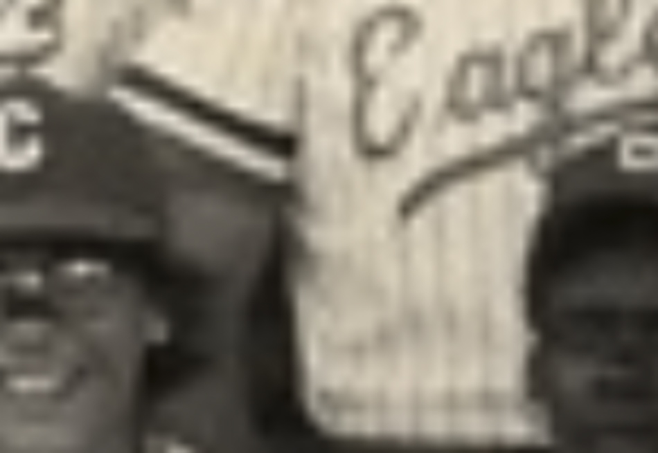 MATTHEW SWARTS A blurry, sepia-toned photo by photographer Matthew Swarts shows part of three people in baseball uniforms. The center figure’s jersey reads “Eagles,” and two individuals in baseball caps are partly visible at the bottom.