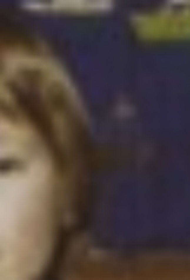 MATTHEW SWARTS A blurry close-up image in the style of fine art photography, showing part of a person’s face with light-colored hair, set against a dark blue background with indistinct shapes or text—evocative of Matthew Swarts’ art.
