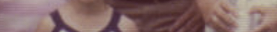 MATTHEW SWARTS A blurry, close-up image in the style of visual art shows part of a person with long, reddish hair and a dark-strapped top. The photo, reminiscent of Matthew Swarts' work, is out of focus and has a pinkish hue.