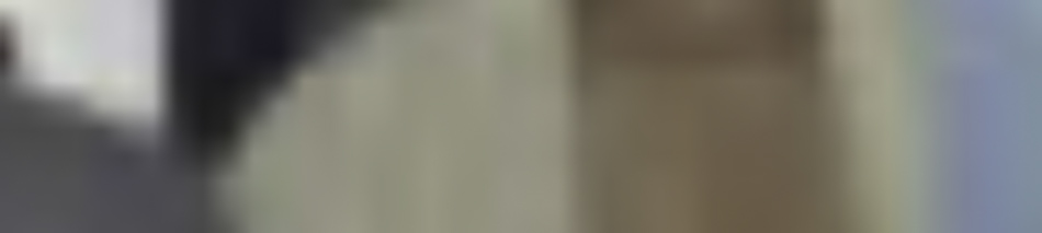 MATTHEW SWARTS The image is very blurry and out of focus, making it difficult to distinguish specific objects or details. The mix of beige, brown, blue, and dark gray evokes the abstract style often seen in contemporary art.