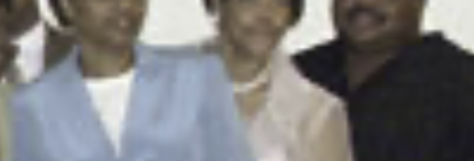 MATTHEW SWARTS A group of three adults, reminiscent of a MATTHEW SWARTS visual art piece, stand close together—two women in light outfits and a man in a dark shirt—posing for a photo against a light background. The image is blurry.