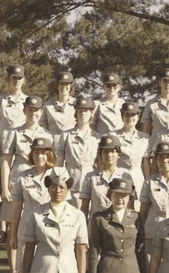 MATTHEW SWARTS A group of women in light-colored military uniforms and hats stand outdoors in rows, posing for a group photo with trees in the background, reminiscent of a CONTEMPORARY ART piece capturing unity and strength.