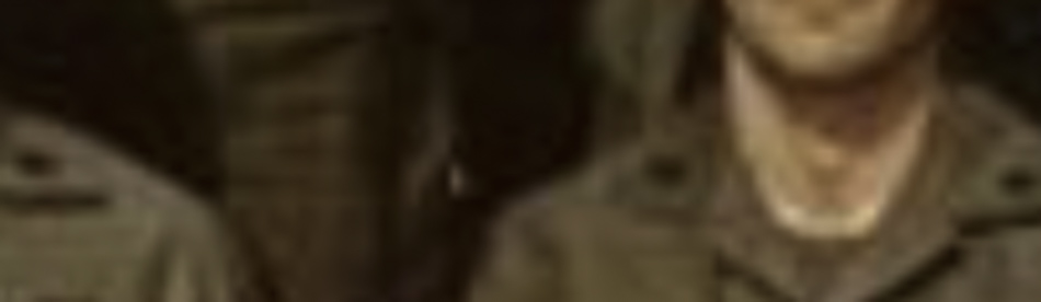 MATTHEW SWARTS A cropped, blurry image in the style of fine art photography shows part of a person wearing a brown military-style uniform, with only the lower half of their face and chest visible.