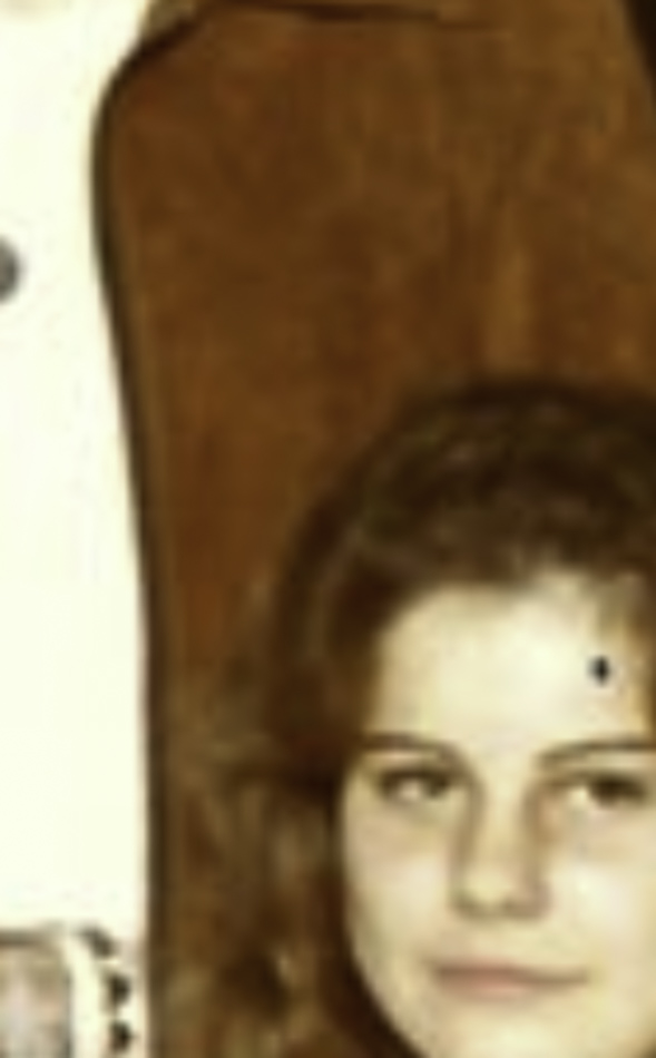 MATTHEW SWARTS A cropped, slightly blurry image showing part of a person’s face with curly hair in front of a brown background. Reminiscent of VISUAL ART by MATTHEW SWARTS, only the top section of the head and a bit of the upper face are visible.