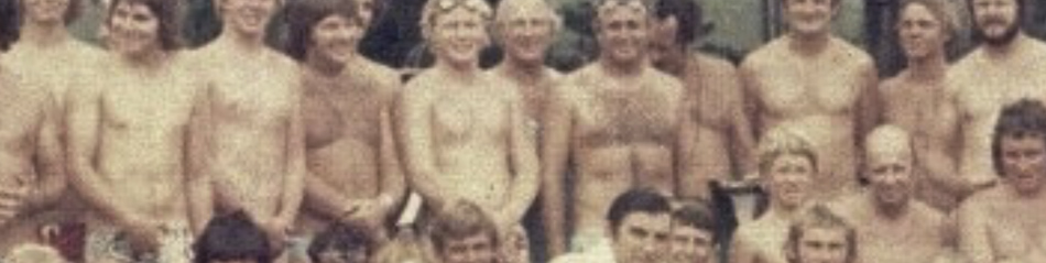 MATTHEW SWARTS A group of shirtless people in swimwear pose closely together outdoors, smiling at the camera. The image, with its vintage, faded look, evokes fine art photography and reveals the artist’s unique visual art perspective.