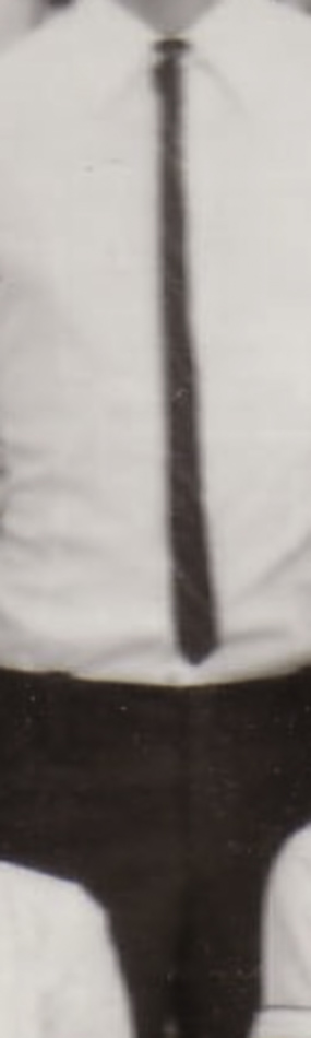 MATTHEW SWARTS A black-and-white photo in the style of contemporary art showing the torso of a person wearing a light-colored dress shirt, a dark tie, and dark pants. The artist captures only the torso, leaving the head and lower body out of frame.