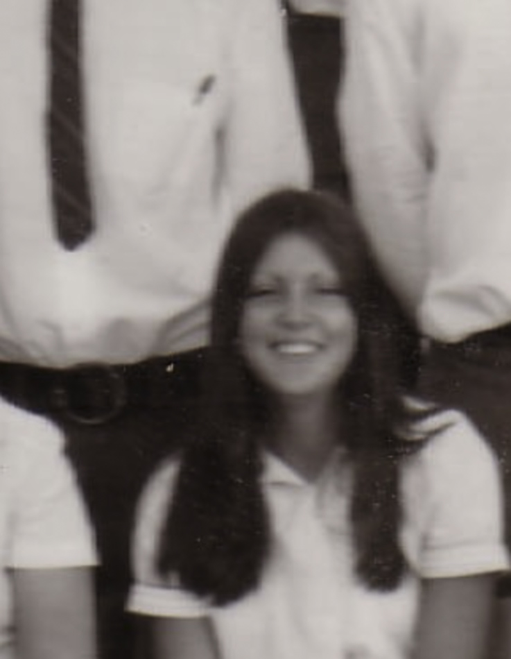 MATTHEW SWARTS A young woman with long hair and a white shirt smiles for a group photo. This black and white image, with people in dress shirts and ties behind her, captures the timeless elegance of fine art photography.