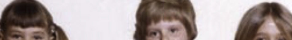 MATTHEW SWARTS A cropped image in the style of fine art photography shows the upper parts of three children's faces—just their eyes, hair, and foreheads—against a plain background.