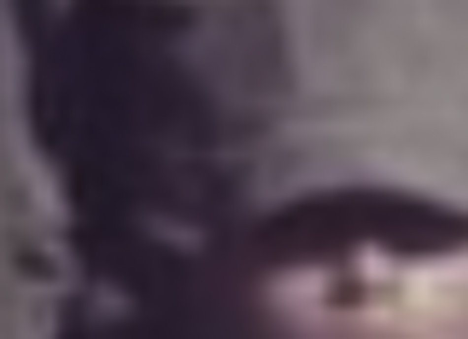 MATTHEW SWARTS A very blurry image in the style of fine art photography, showing the upper part of a person’s face, partially obscured by a hat, with indistinct background details.