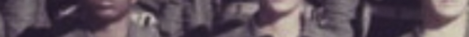 MATTHEW SWARTS Blurry and cropped image showing the torsos of people in green or brown clothing standing close together. Their faces and surroundings are not clearly visible, reflecting elements of fine art photography.