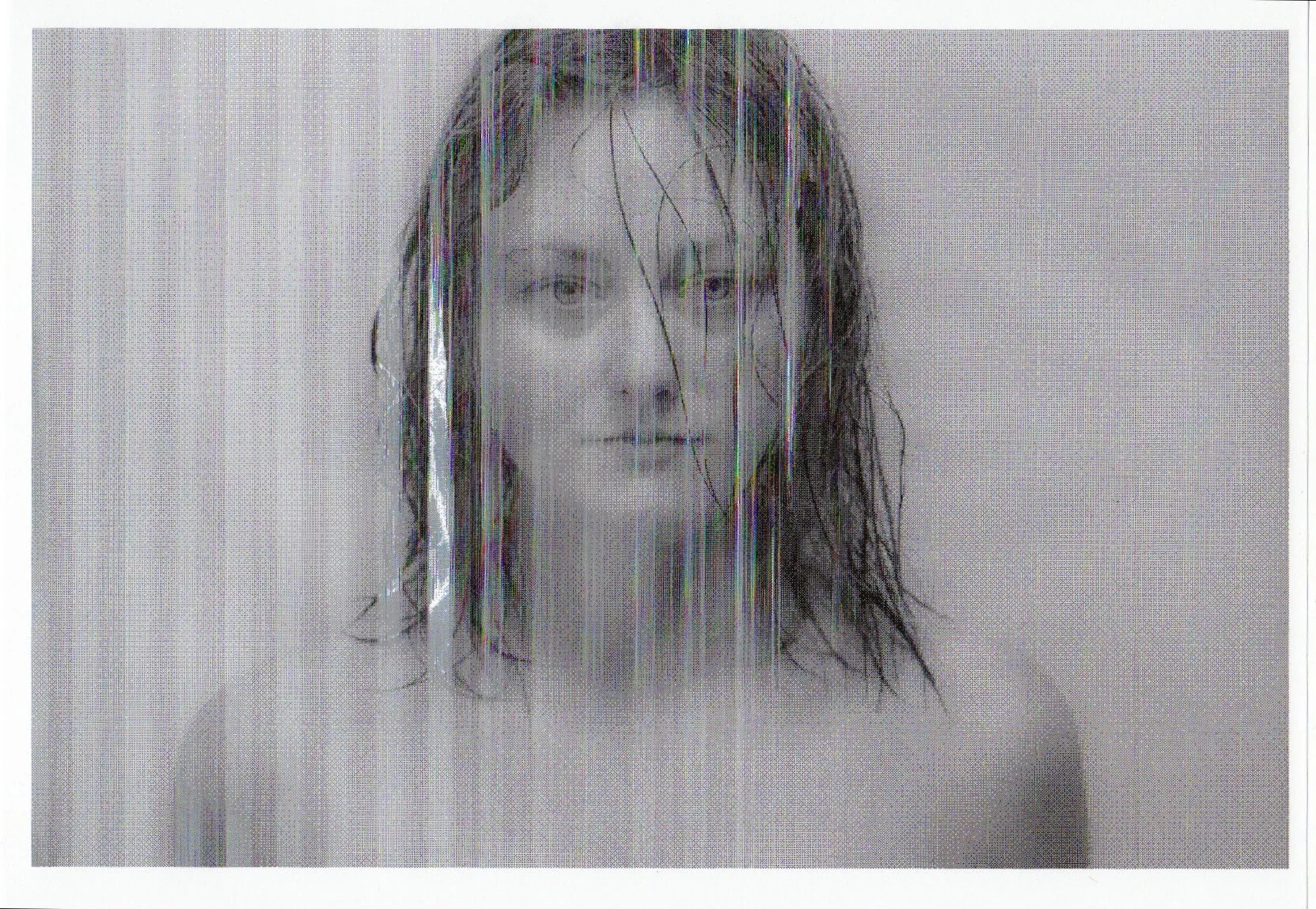 MATTHEW SWARTS A grayscale photo by artist Matthew Swarts shows a person with wet hair standing behind a semi-transparent, striped surface, looking directly at the camera as the image appears slightly distorted by vertical lines.